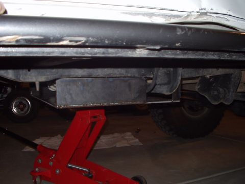 1993 Ford Bronco - The underside of a vehicle is shown with a red jack supporting a newly installed skid plate.
