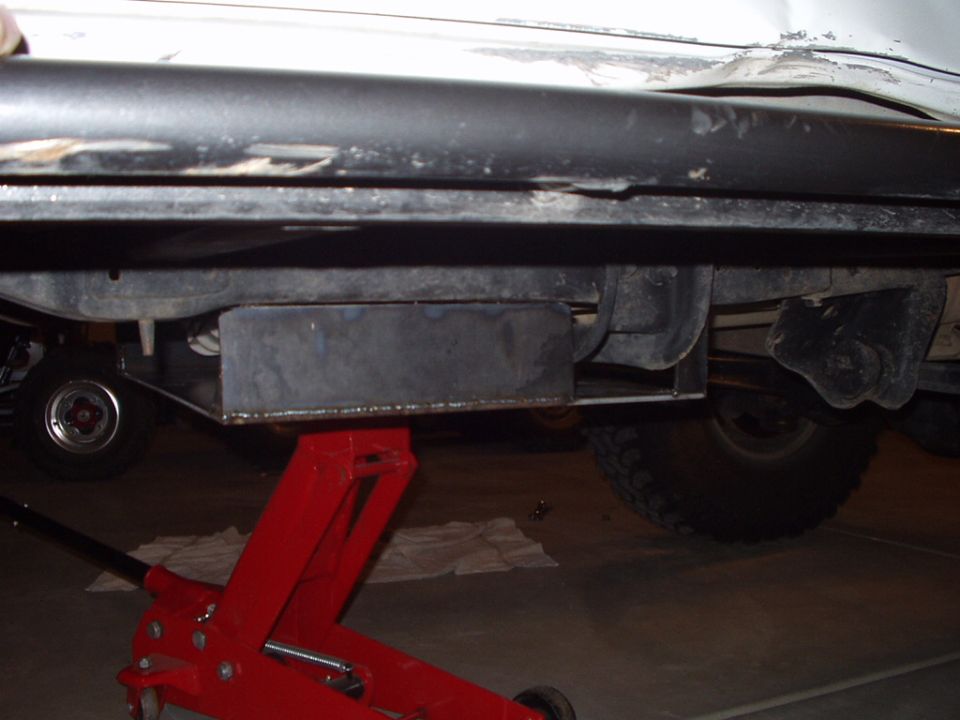 Underside of vehicle with metal skid plate on red floor jack