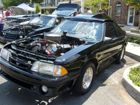 2007 Ford Mustang - A black Ford Mustang, likely from the late 1980s, is displayed with its hood open at an outdoor car show.