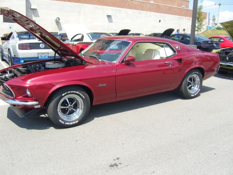 2007 Ford Mustang - A classic red Ford Mustang is displayed at an outdoor car show, with its hood open to reveal the engine.