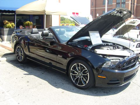 2007 Ford Mustang - Black convertible Mustang with hood open at a car show, another vehicle visible behind.