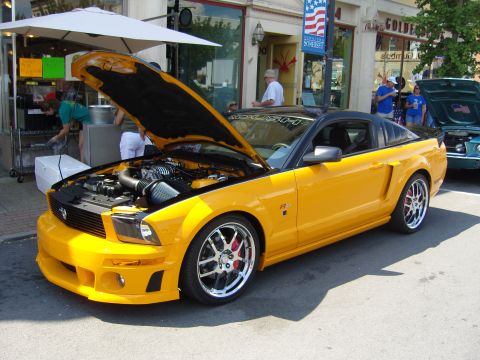 2007 Ford Mustang - A yellow 2007 Ford Mustang is displayed with its hood open at an outdoor event.