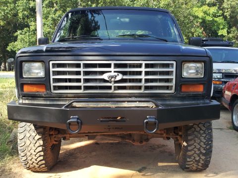 1986 Ford Bronco - Front view of a black Ford Bronco with a custom bumper and off-road tires, parked outdoors.