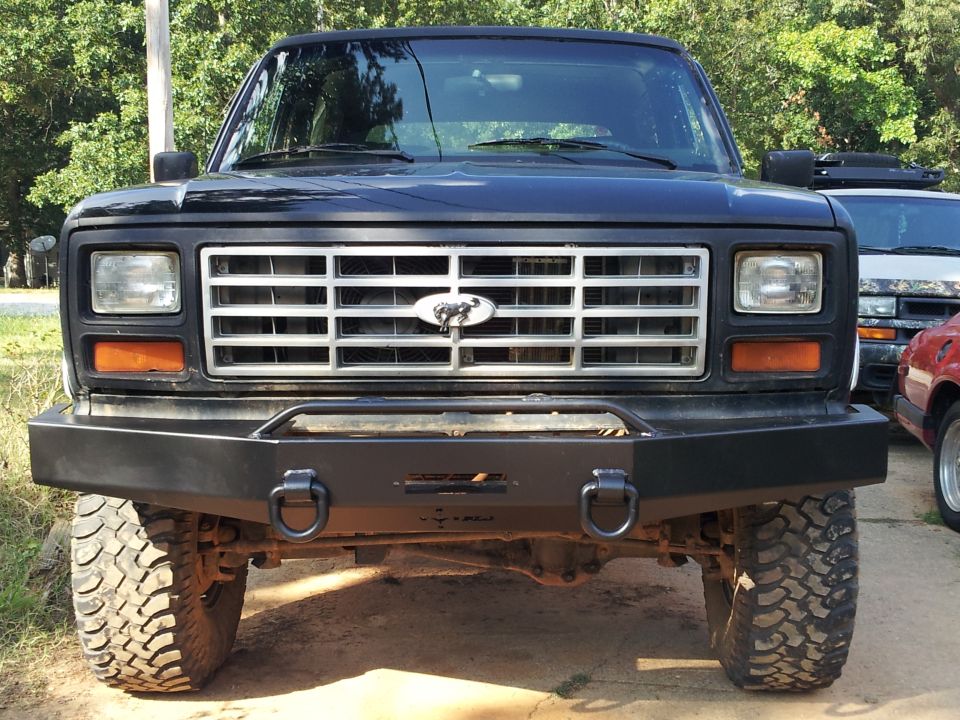 Black Ford Bronco front view with aftermarket bumper and large tires. Grille has a Ford emblem