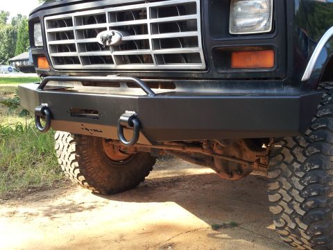 1986 Ford Bronco - Close-up of the front of a 1980s Ford Bronco, highlighting its heavy-duty bumper and tow hooks.