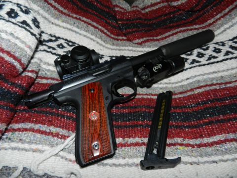 1996 Ford Bronco - A pistol with aftermarket accessories, including a suppressor and tactical light, rests on a patterned blanket next to its magazine.