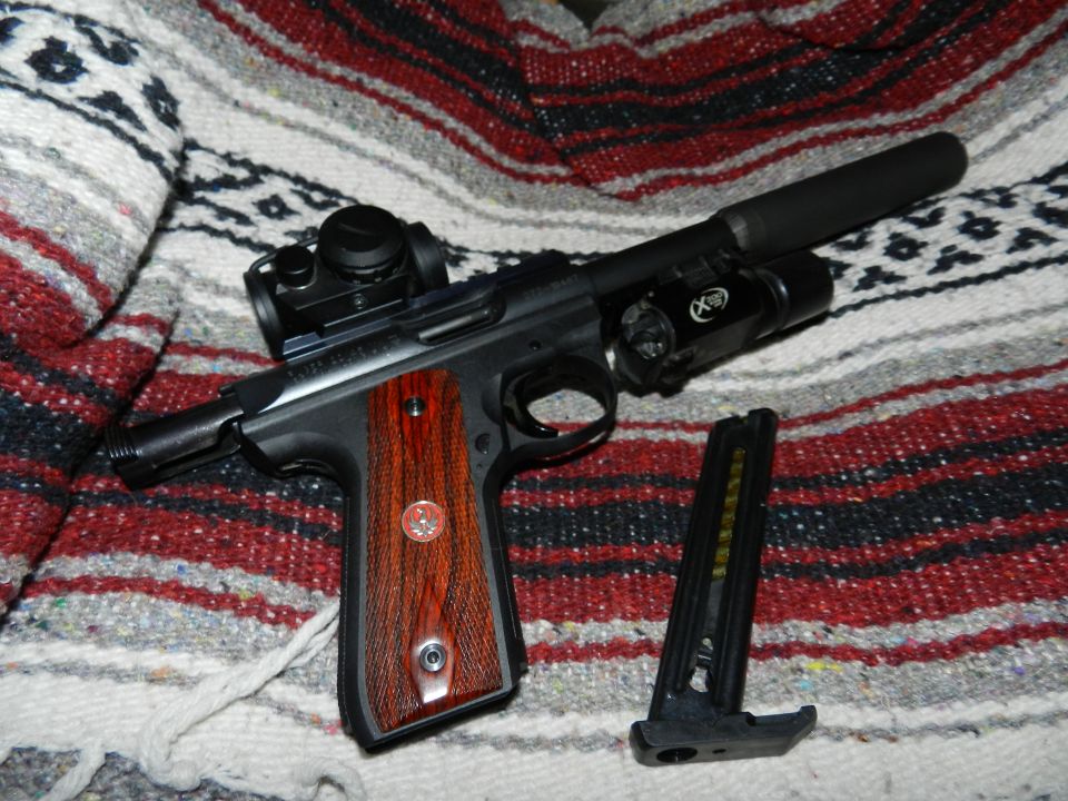 Pistol with red dot sight, suppressor, and flashlight on a blanket