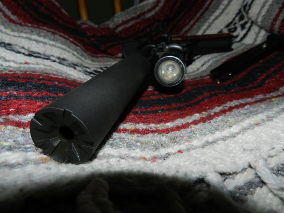 Gun with silencer and flashlight on a blanket
