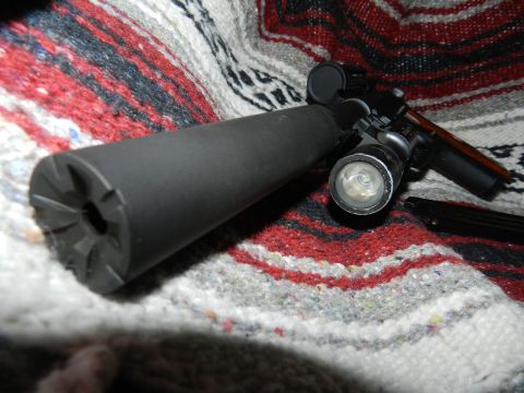 1996 Ford Bronco - Firearm with suppressor and flashlight mounted on a blanket.