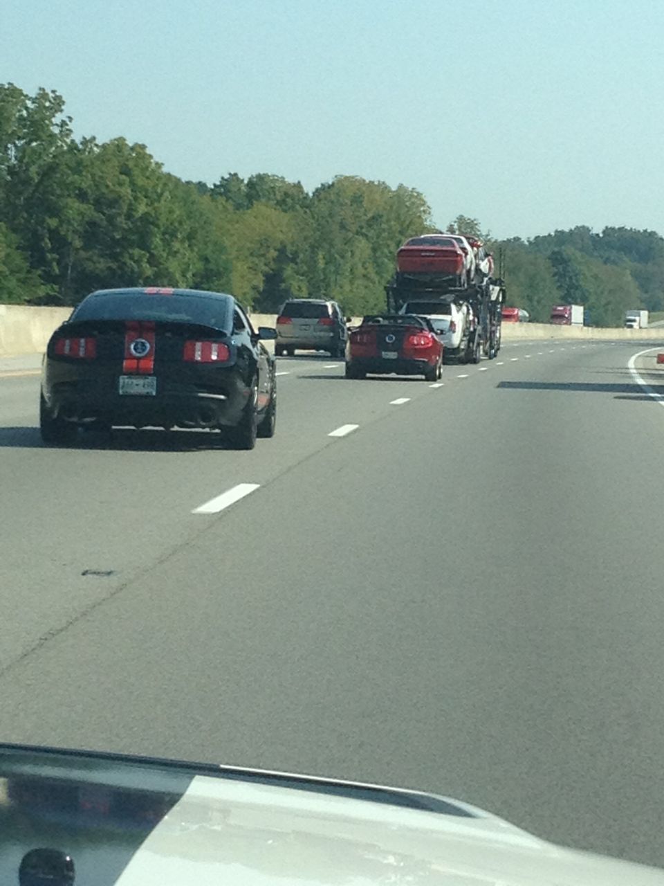 Black 2007 Ford Mustang with red stripes on rear, driving on highway