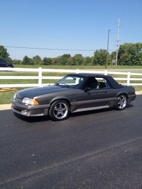 2007 Ford Mustang - Gray convertible Mustang with black top and chrome wheels parked on asphalt.