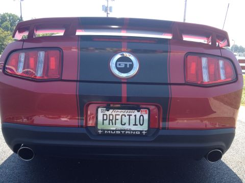 2007 Ford Mustang - Rear view of a red Ford Mustang GT with black racing stripes and a Tennessee license plate.