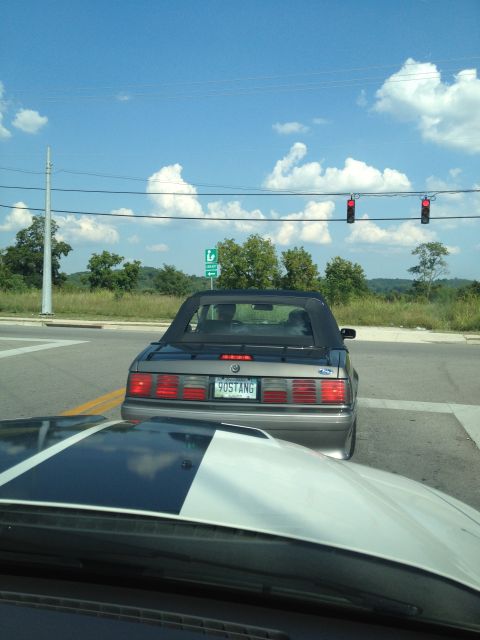 2007 Ford Mustang - A gray convertible Mustang with a black top is seen from behind at a traffic light.