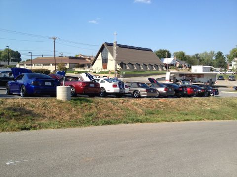2007 Ford Mustang - A line of Mustangs are parked in a lot, with a church visible behind them on a sunny day.