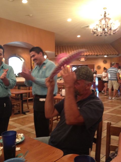 2007 Ford Mustang - A man in a restaurant is holding a large pink fan in front of his face while others look on.