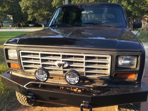 1986 Ford Bronco - Front view of a black Ford Bronco, likely from the early 1980s, with an aftermarket bumper and auxiliary lights.
