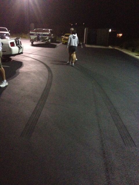 2007 Ford Mustang - A white 2007 Ford Mustang with racing stripes is parked on asphalt, leaving tire marks from a recent maneuver.