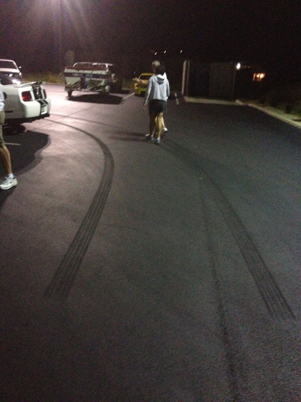 Rear view of white 2007 Ford Mustang with racing stripes, showing tire marks on asphalt