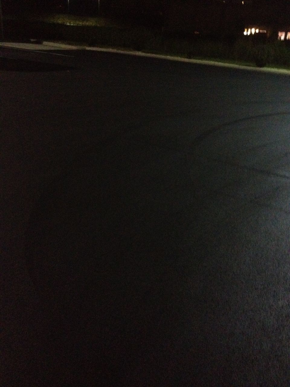 Dark asphalt with tire marks under faint lighting