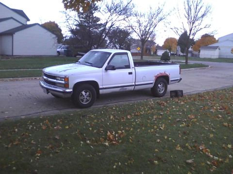 2003 Ford Crown Victoria - A white pickup truck is parked on the side of the road during autumn.