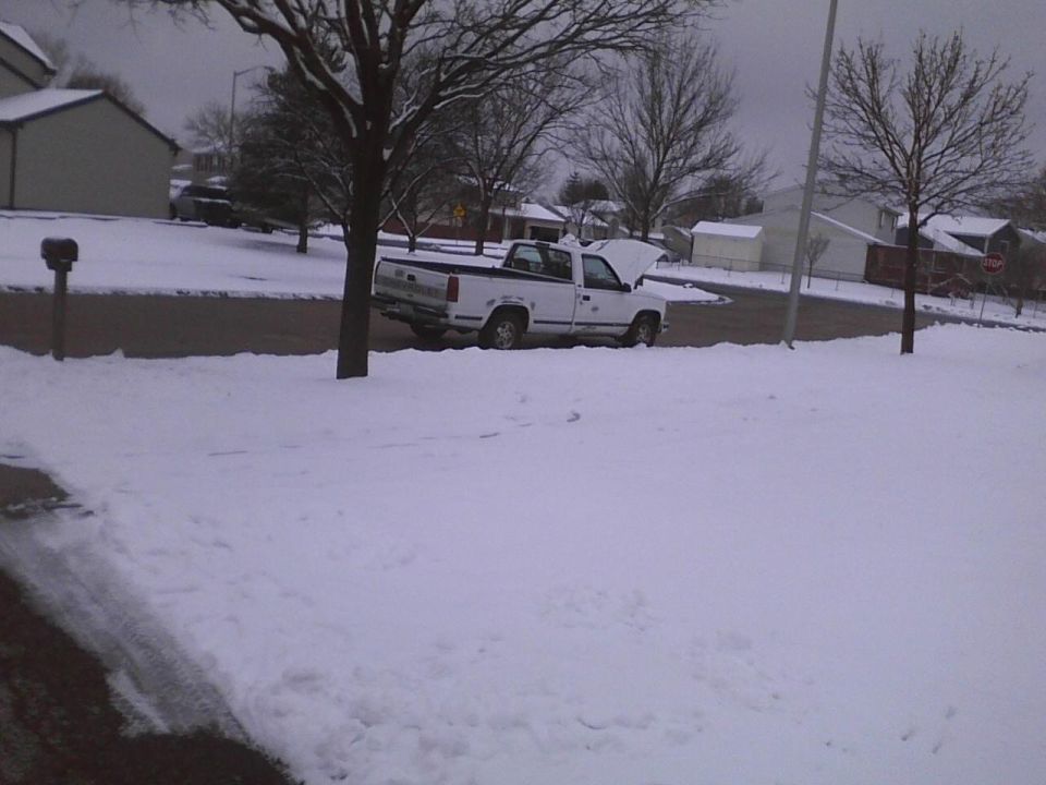White pickup truck with hood open parked on a snow-covered street