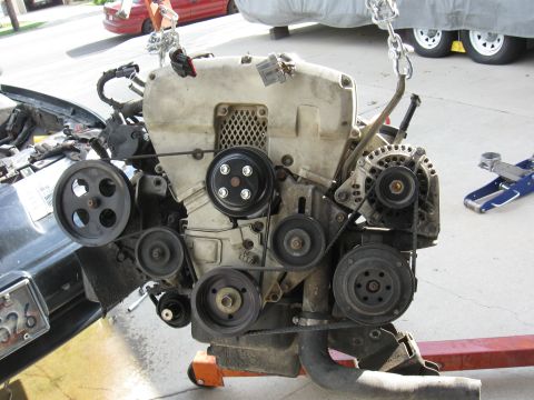 1992 Ford Taurus - Engine assembly, likely removed from a vehicle, is suspended by chains and resting on an engine stand.