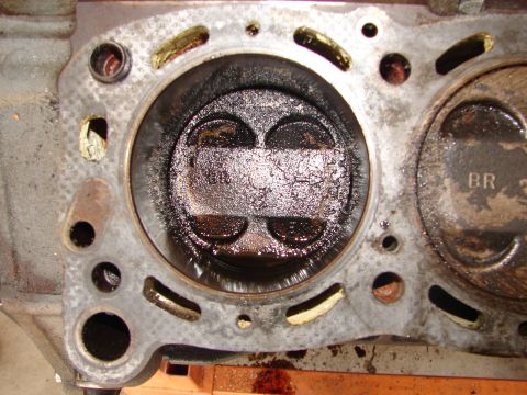 1992 Ford Taurus - This is a close-up view of a heavily carbonized engine cylinder and piston, with visible markings on an adjacent piston.