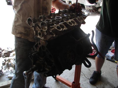 1992 Ford Taurus - Engine block assembly being worked on by mechanics in a garage setting.