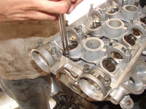 1992 Ford Taurus - Close-up of an engine cylinder head being worked on, showing internal components and a hand with a tool.