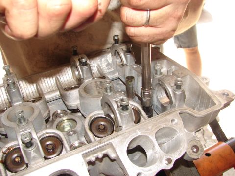 1992 Ford Taurus - Mechanic works on an engine's cylinder head, using a socket wrench to tighten a bolt.