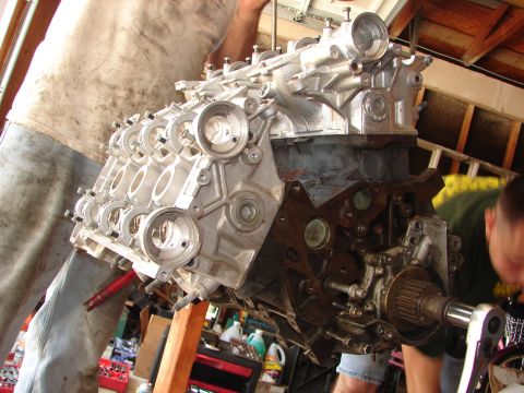 1992 Ford Taurus - Engine assembly is underway with a mechanic attending to the components.