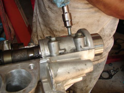 1992 Ford Taurus - Close-up of a mechanic's hands working on an engine part with a socket wrench.