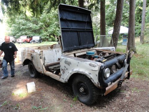 1962 International Scout 80 - A weathered International Scout sits in a wooded area with its hood open, revealing the engine.