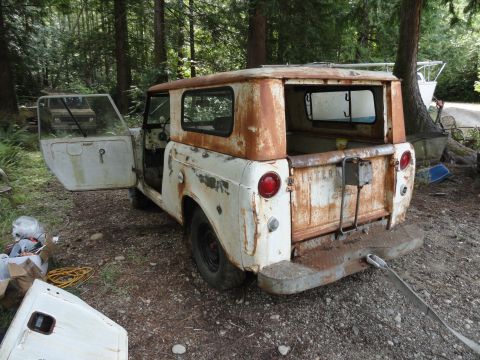 1962 International Scout 80 - This heavily rusted International Scout is parked outdoors with its doors open, showing another vehicle in the background.