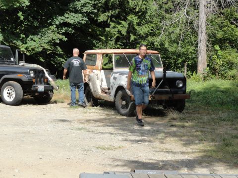 1962 International Scout 80 - Two men stand near a weathered International Scout and a black Jeep on a sunny day.
