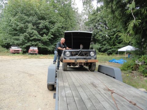 1962 International Scout 80 - A man loads a 1962 International Scout 80 onto a trailer, with two other similar vehicles visible in the background.
