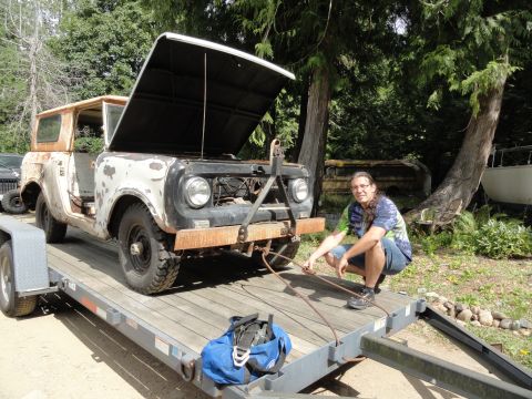 1962 International Scout 80 - A person is near a 1962 International Scout 80 loaded onto a trailer, with its hood open.
