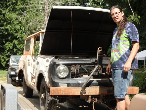 1962 International Scout 80 - A man stands beside a weathered International Scout 80, its hood raised to reveal the engine compartment.