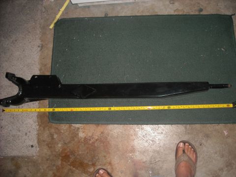 1992 Ford Bronco - A black metal automotive part is measured with a yellow tape measure on a dark green mat.