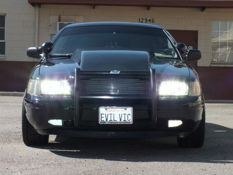 2003 Ford Crown Victoria - Black Crown Victoria shows a billet grille, push bar, lit headlights and EVIL VIC plate.