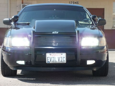 2003 Ford Crown Victoria - Crown Victoria faces forward with bright headlights, brush guard and California EVIL VIC plate.
