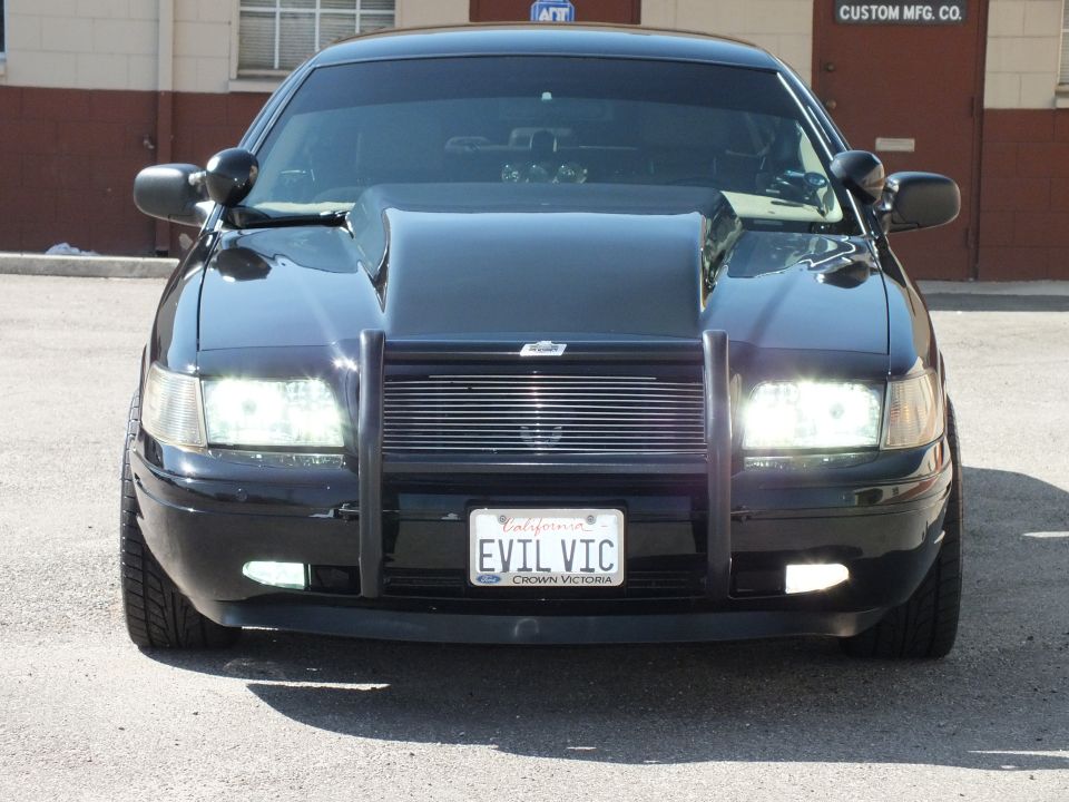 Black Crown Victoria front with push bar and EVIL VIC plate by Custom Mfg Co building