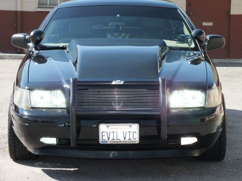 2003 Ford Crown Victoria - Close front view of a black Crown Victoria with fog lights, brush guard and EVIL VIC plate.