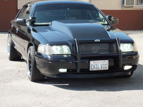 2003 Ford Crown Victoria - Lowered black Crown Victoria sits on chrome-lip wheels with a brush guard and EVIL VIC plate.