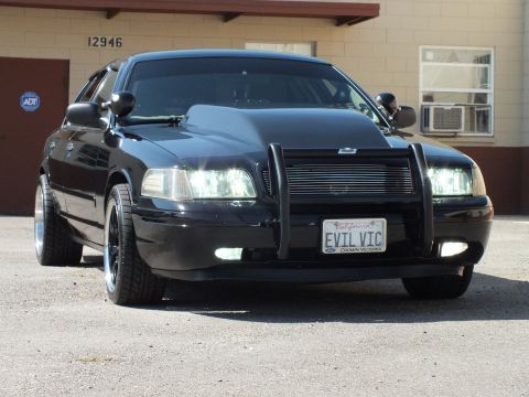 2003 Ford Crown Victoria - Black Crown Victoria angled front view shows brush guard, fog lights and chrome-lip wheels.