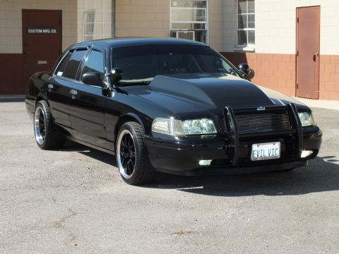 2003 Ford Crown Victoria - Front-quarter view of a black Crown Victoria on black wheels with push bar and fog lights.