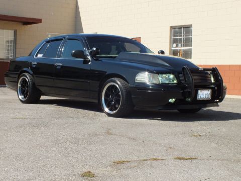 2003 Ford Crown Victoria - Lowered black Crown Victoria seen at a front angle with brush guard and chrome-lip wheels.