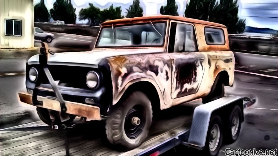 Rusty International Scout on a trailer, front end visible, cracked windshield