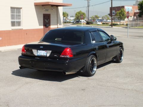 2003 Ford Crown Victoria - Rear view of a black Crown Victoria sedan with Ford oval, SVT badge and a California plate on black wheels.