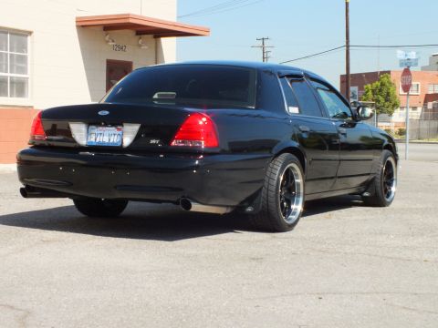 2003 Ford Crown Victoria - Rear three-quarter of a black Crown Victoria with SVT badge and California plate near a stop sign.